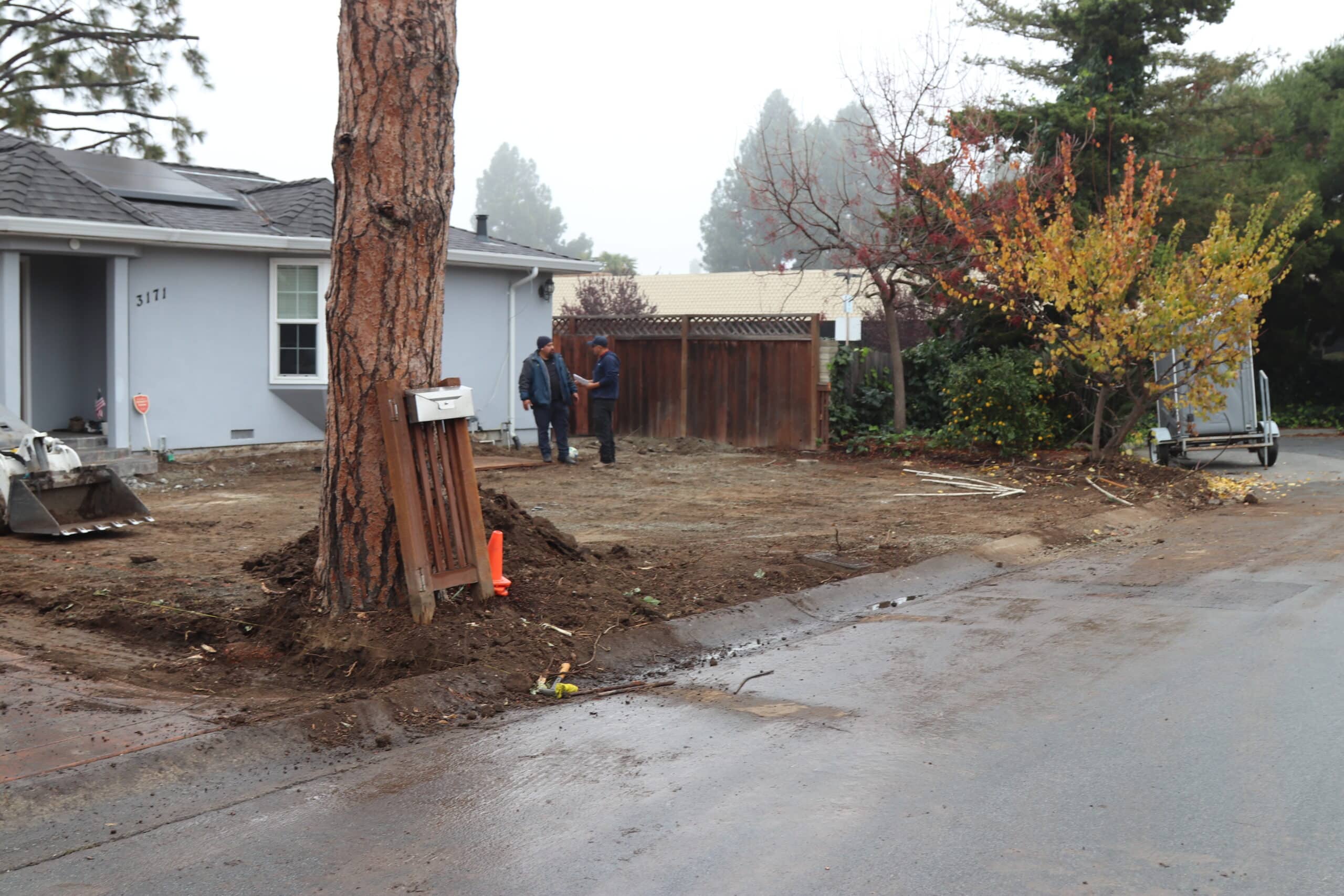 Tree work in progress at residential property with protective padding and workers clearing defensible space